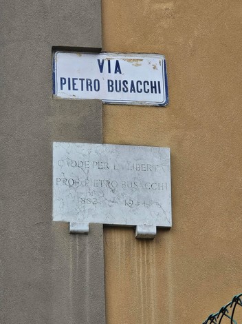 Lapide commemorativa dedicata a Pietro Busacchi, situata all'angolo di una via.