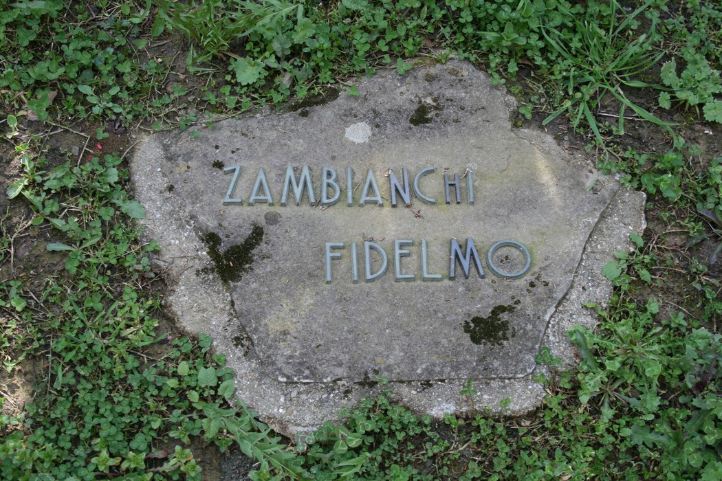 Monumento commemorativo nel cimitero di Stia, dedicato a Fidelmo Zambianchi, immerso nel verde.