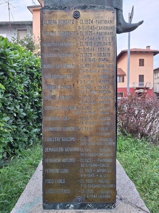 Lapide in bronzo con lungo elenco di nomi dei caduti, montata su basamento in pietra all'aperto.