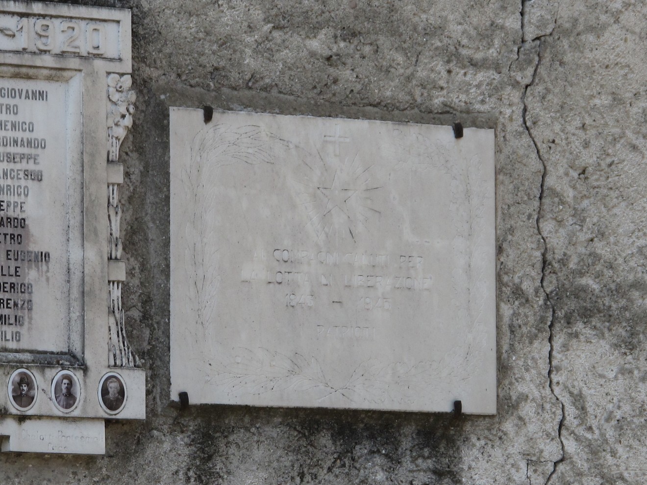 Lapide commemorativa in omaggio ai compagni caduti, incisa su marmo, con simboli decorativi.