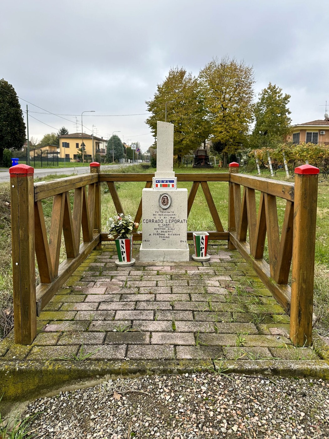 Cippo commemorativo a Leporati, dedicato a Corrado Leporati, circondato da un giardino curato.