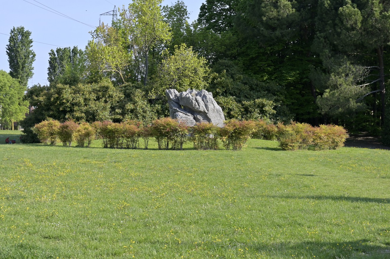 Monumento alla Resistenza circondato da alberi e un prato verde, in un ambiente tranquillo e alberato.