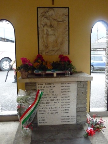 Cappella in memoria dei partigiani caduti, con fiori e lapide commemorativa. Ambiente sobrio e rispettoso.
