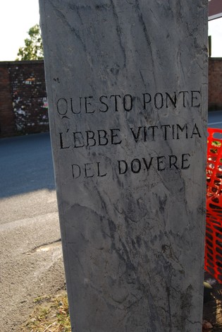 Cippo commemorativo che ricorda l'incidente avvenuto su un ponte, inciso su una pietra.
