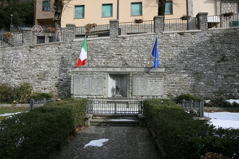 Monumento commemorativo ai caduti di Badia Prataglia, con bandiere e un'area verde circostante.