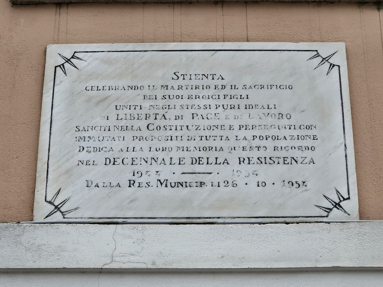 Lapide commemorativa per il decennale della Resistenza, celebrando i sacrifici e la libertà.