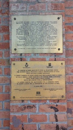 Lapidi commemorative delle Caserme Rosse, su muro di mattoni, con testi informativi sulla storia del luogo.