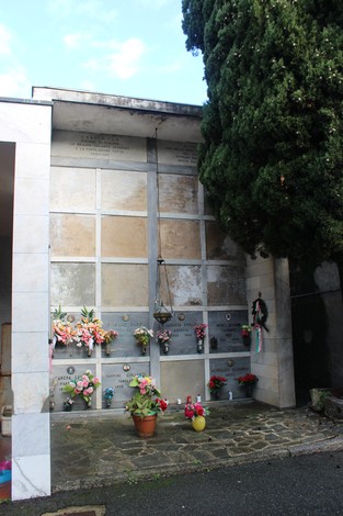 Sacrario dei partigiani con decorazioni floreali e lumini, ambiente tranquillo e commemorativo.