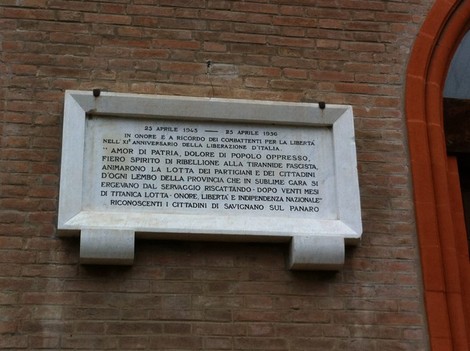 Lapide commemorativa dedicata alla Liberazione, collocata su un edificio, con date significative e messaggio di onore ai patrioti.