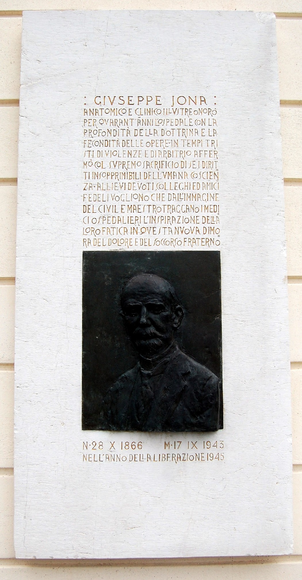 Lapide commemorativa dedicata a Giuseppe Jona, con un rilievo in bronzo e testo descrittivo in alto.