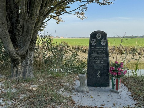 Monumento commemorativo a Alcorini, Cavazzoli e Gasparini, immerso nel verde, vicino a un corso d’acqua.