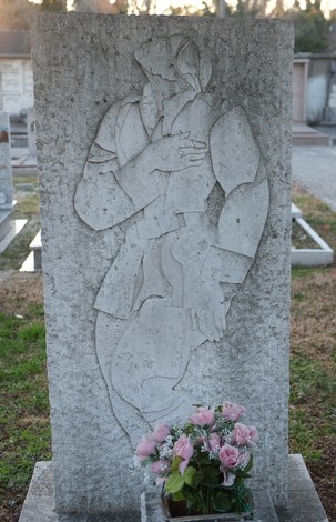 Tomba di Andrijic con rilievo artistico e bouquet di fiori, situata in un cimitero.