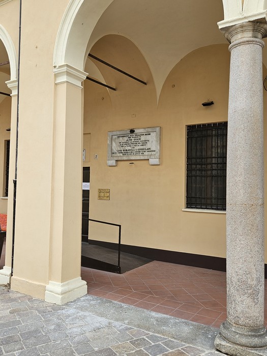 Lapide commemorativa dedicata ai caduti per la libertà, situata in un'area con architettura storica.