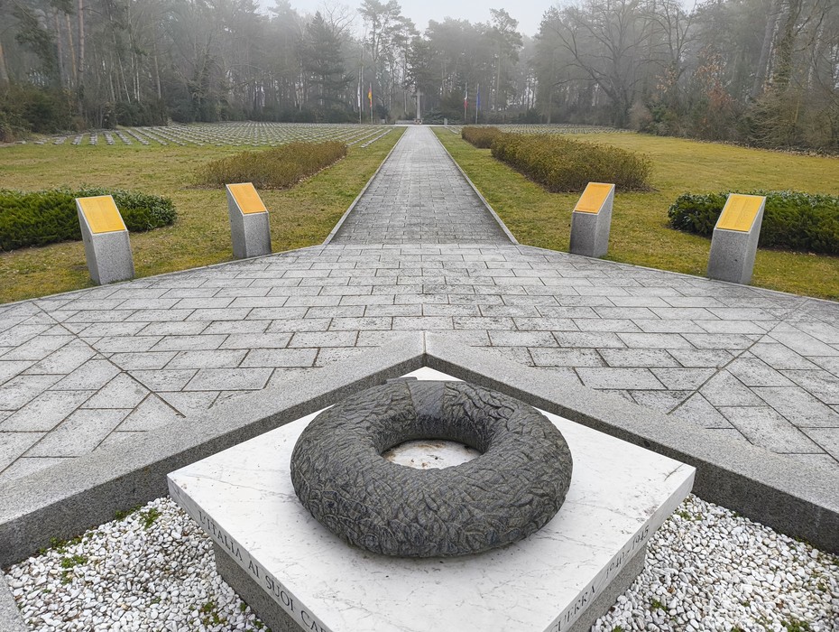 Cimitero militare italiano di Zehlendorf con un sentiero centrale e monumento commemorativo circondato da alberi.