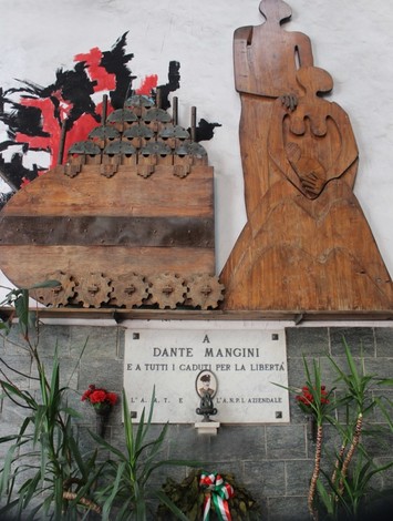 Monumento commemorativo dedicato a Dante Mangini, con sculture che rappresentano libertà e memoria.
