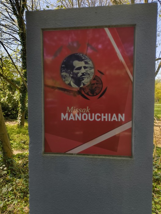 Memoriale dedicato a Missak Manouchian, con immagine e design moderno immerso nella natura.