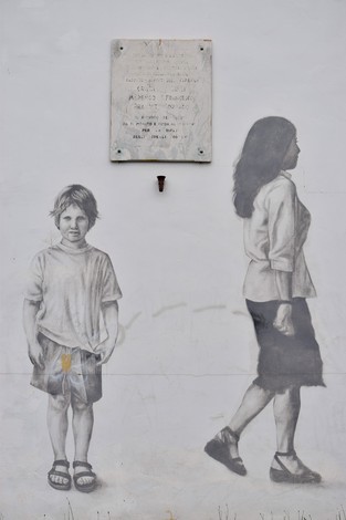 Lapide dedicata ai Sappisti della Superga, affiancata da murales che raffigurano due figure umane.