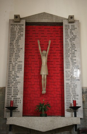 Sacrario nella chiesa di San Pancrazio, con statue e nomi commemorativi su una parete rossa.