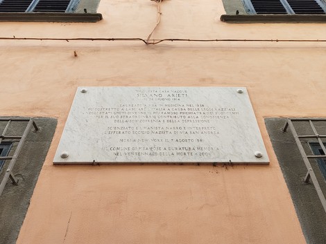 Lapide commemorativa dedicata a Silvano Arieti, situata su un edificio di colore arancione.