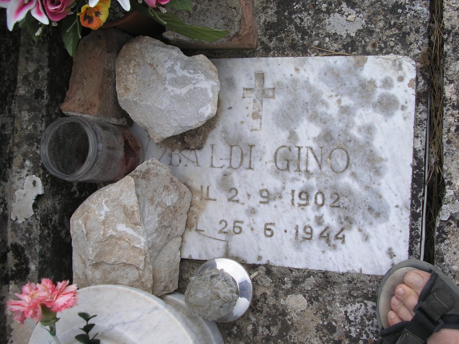 Targa commemorativa nel Sacrario dei partigiani, con fiori e pietre in ricordo dei caduti.