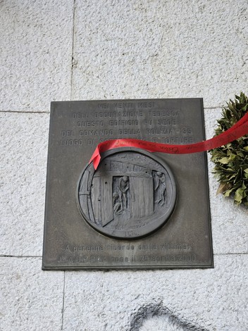 Targa commemorativa posta sulla facciata della sede del comando Polizia-SS, con un nastro rosso.
