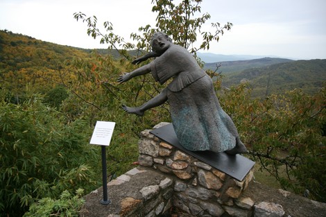 Scultura rappresentante un chierichetto, situata in un'area panoramica tra le colline, circondata dalla natura.