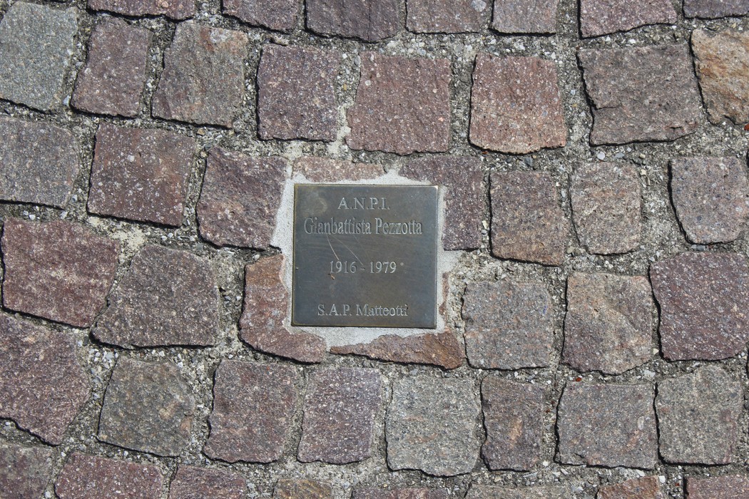 Pietre d'inciampo in memoria di partigiani, collocate su un pavimento di ciottoli.