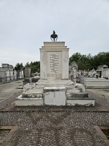 Monumento ai Caduti della Resistenza, circondato da elementi funerari in un cimitero, con un'iscrizione commemorativa.