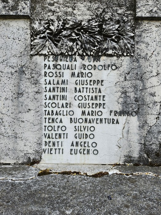 Monumento ai Caduti con iscrizioni commemorative su una parete di pietra.