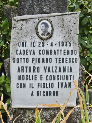 Cippo commemorativo dedicato a Arturo Valzania, posto tra la vegetazione, in ricordo della sua caduta in battaglia.