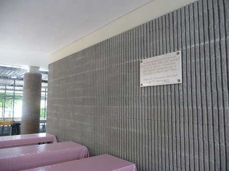 Lapide commemorativa alla Banda Turani in un contesto architettonico semplice e moderno.