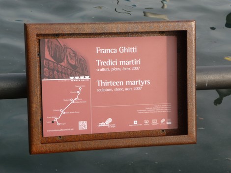 Monumento ai Tredici Martiri, scultura in pietra, situato accanto all'acqua, con un cartello informativo.