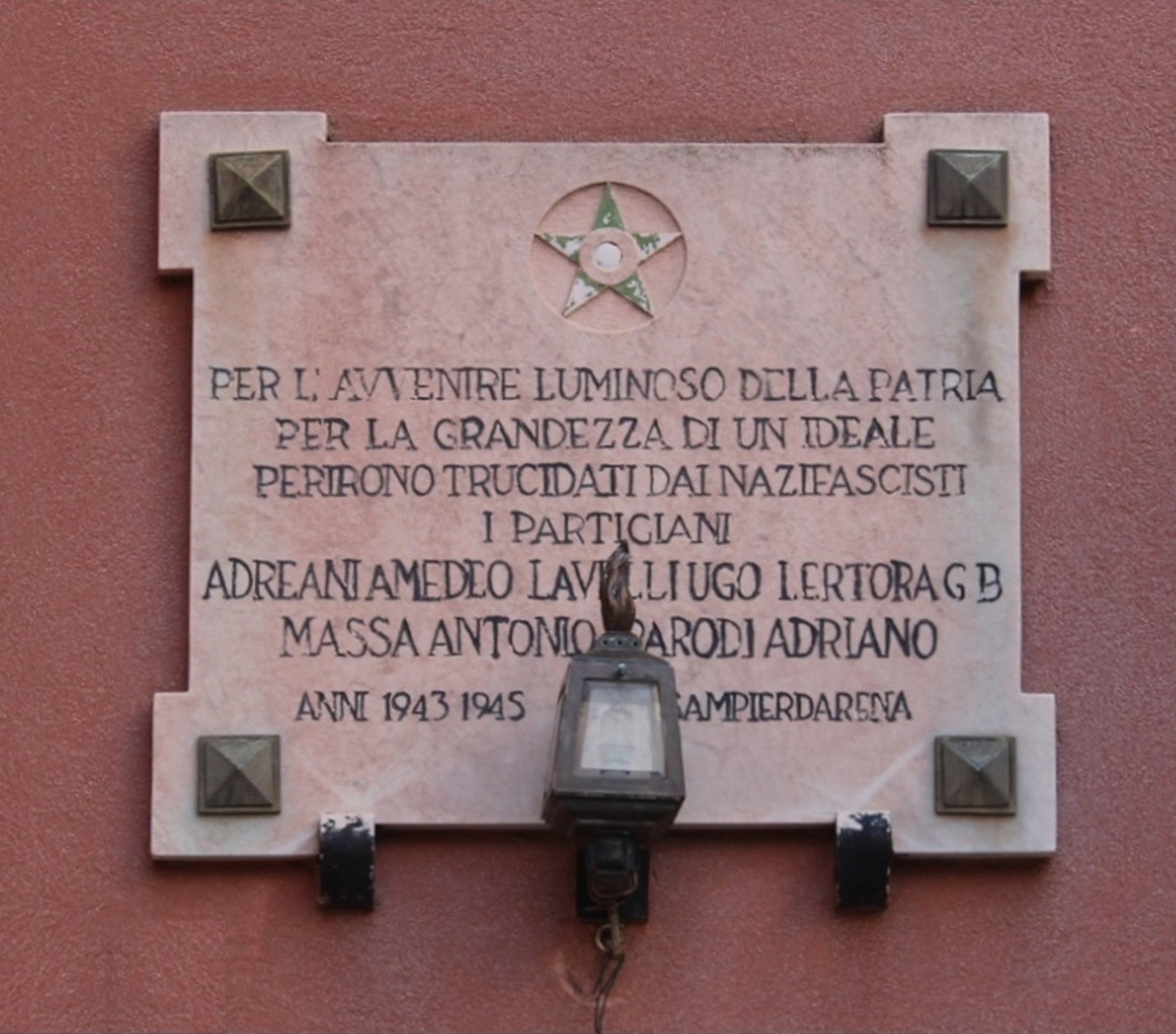 Lapide commemorativa ai partigiani caduti di Promontorio, decorata con una stella e una lampada.
