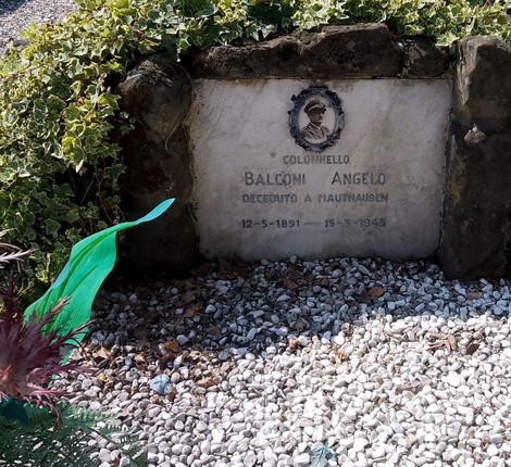 Sepolcro di Balconi con lapide commemorativa circondata da piante e ghiaia.