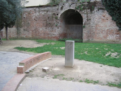 Cippo dedicato all'antifascismo, situato in un'area verde circondata da un muro storico.