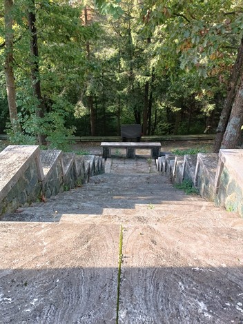 Scalinata che conduce al memoriale dei caduti della Benedicta, circondato da alberi e natura.