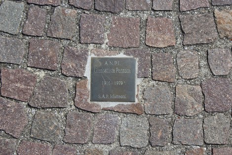 Pietre d'inciampo in memoria di partigiani, collocate su un pavimento di ciottoli.