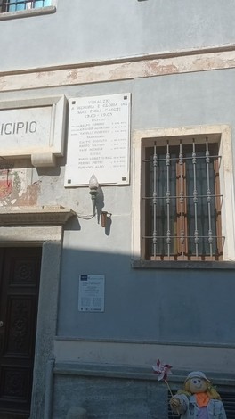 Lapide commemorativa dedicata ai caduti, situata su un edificio pubblico, con diverse targhe in memoria.