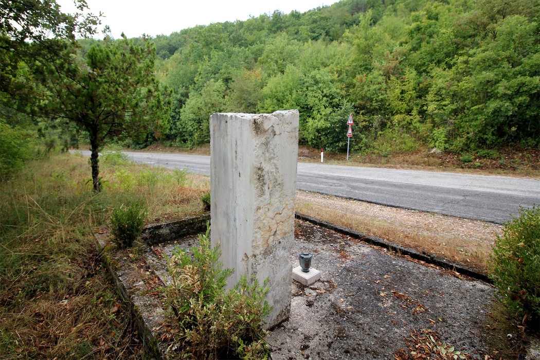 Cippo commemorativo dedicato ai partigiani uccisi, immerso nella natura a Colle di Postignano.