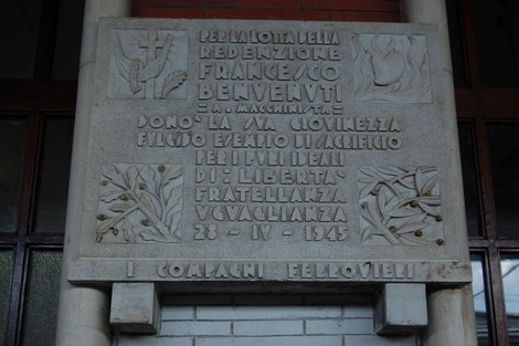 Lapide commemorativa dedicata a Francesco Benvenuti, con decorazioni in rilievo e un messaggio di ricordo.