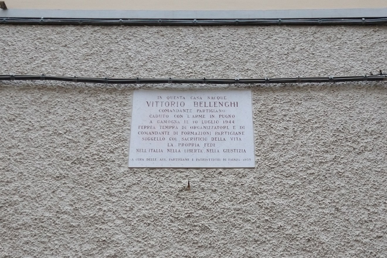 Lapide commemorativa di Vittorio Bellenghi, partigiano, situata sulla facciata di una casa storica.