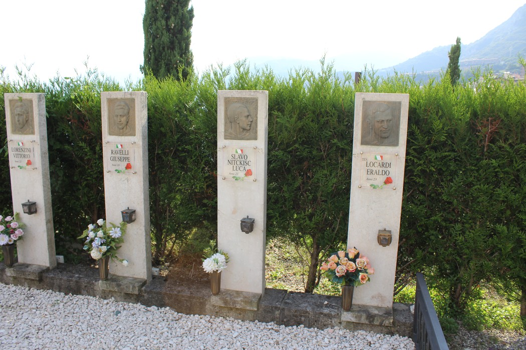 Il Sacrario dei Tredici Martiri, con stele commemorative e fiori, immerso in un paesaggio verde e panoramico.