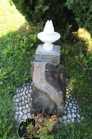 Cippo commemorativo dedicato ai fratelli Mazzola, posizionato su una base di pietra e circondato da vegetazione.