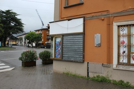Angolo di un edificio con un'insegna vuota e un muro in lamiera, in un contesto urbano di giorno.