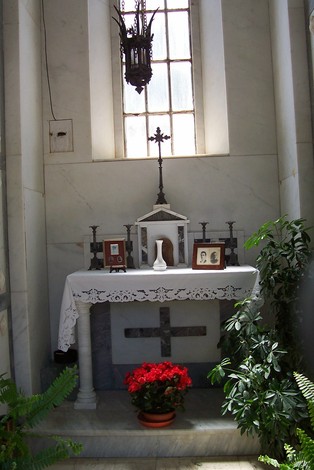 Interno della Cappella dei Caduti di Istia d'Ombrone, con altare, piante e decorazioni commemorative.