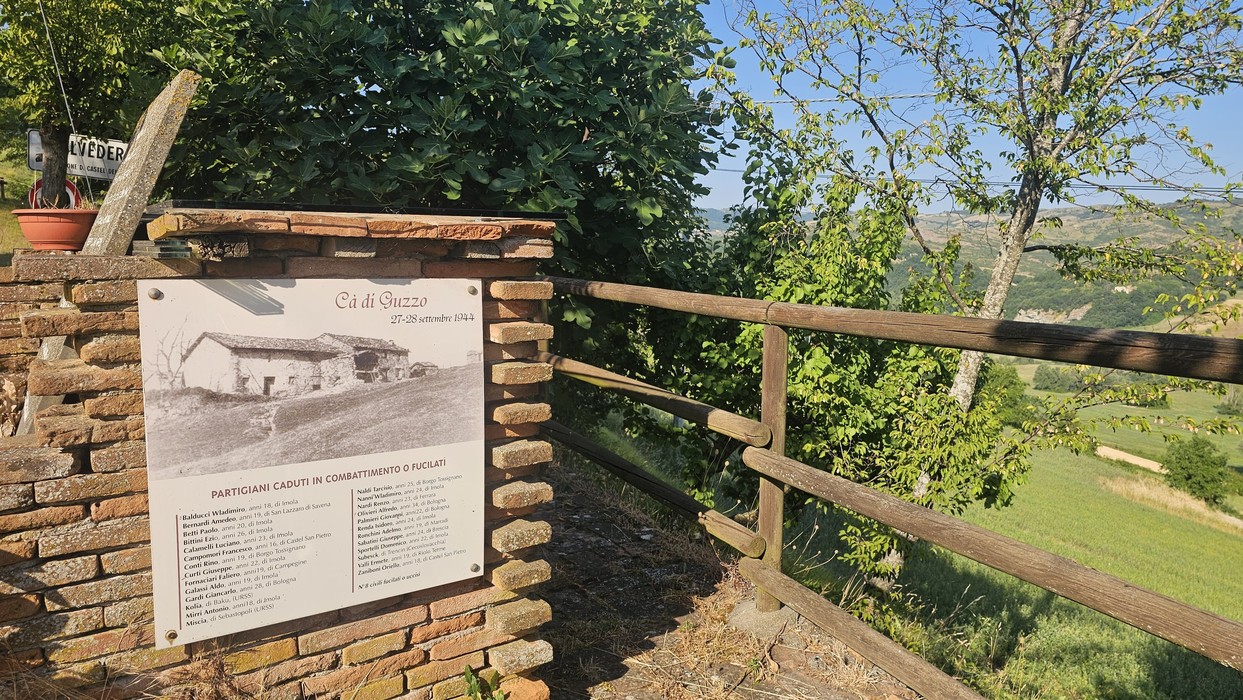 Monumento commemorativo a Ca' di Guzzo, circondato da vegetazione e con vista panoramica.