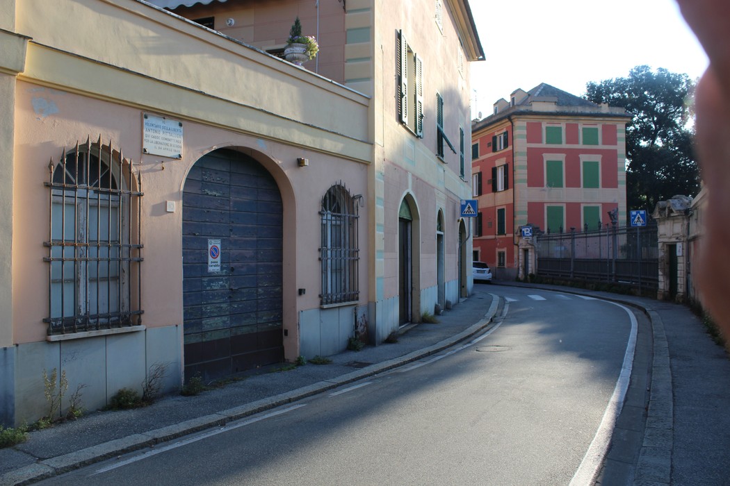 Vista di un vicolo con edifici colorati e una lapide a Pittaluga visibile sui muri. Atmosfera tranquilla e suggestiva.
