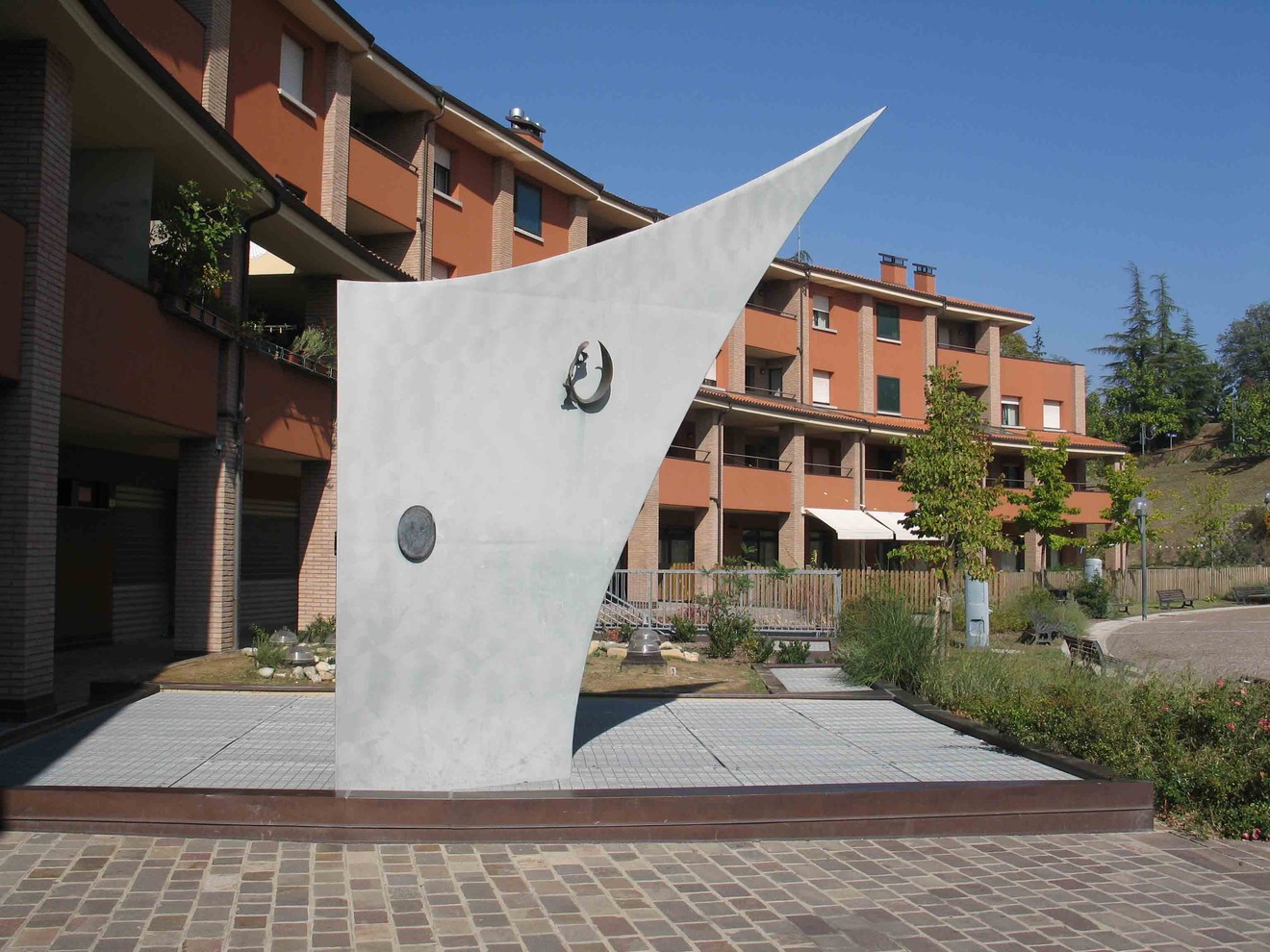 Monumento moderno a Piccinini, caratterizzato da forme geometriche e un design minimalista, circondato da verde.