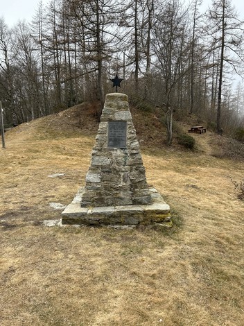 Monumento ai partigiani, struttura commemorativa in pietra circondata da alberi e un'area verde.