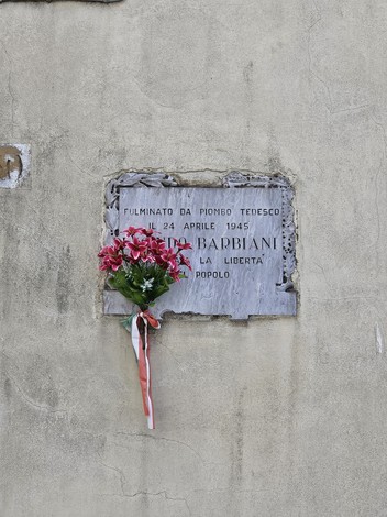 Lapide commemorativa con fiori, in ricordo di Barbiani, vittima di un attacco nel 1945.